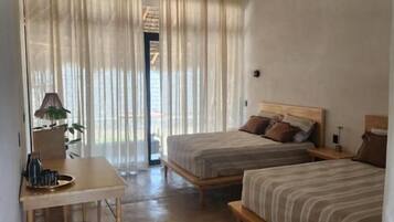 A room with two beds, a small table, and a ceiling fan.