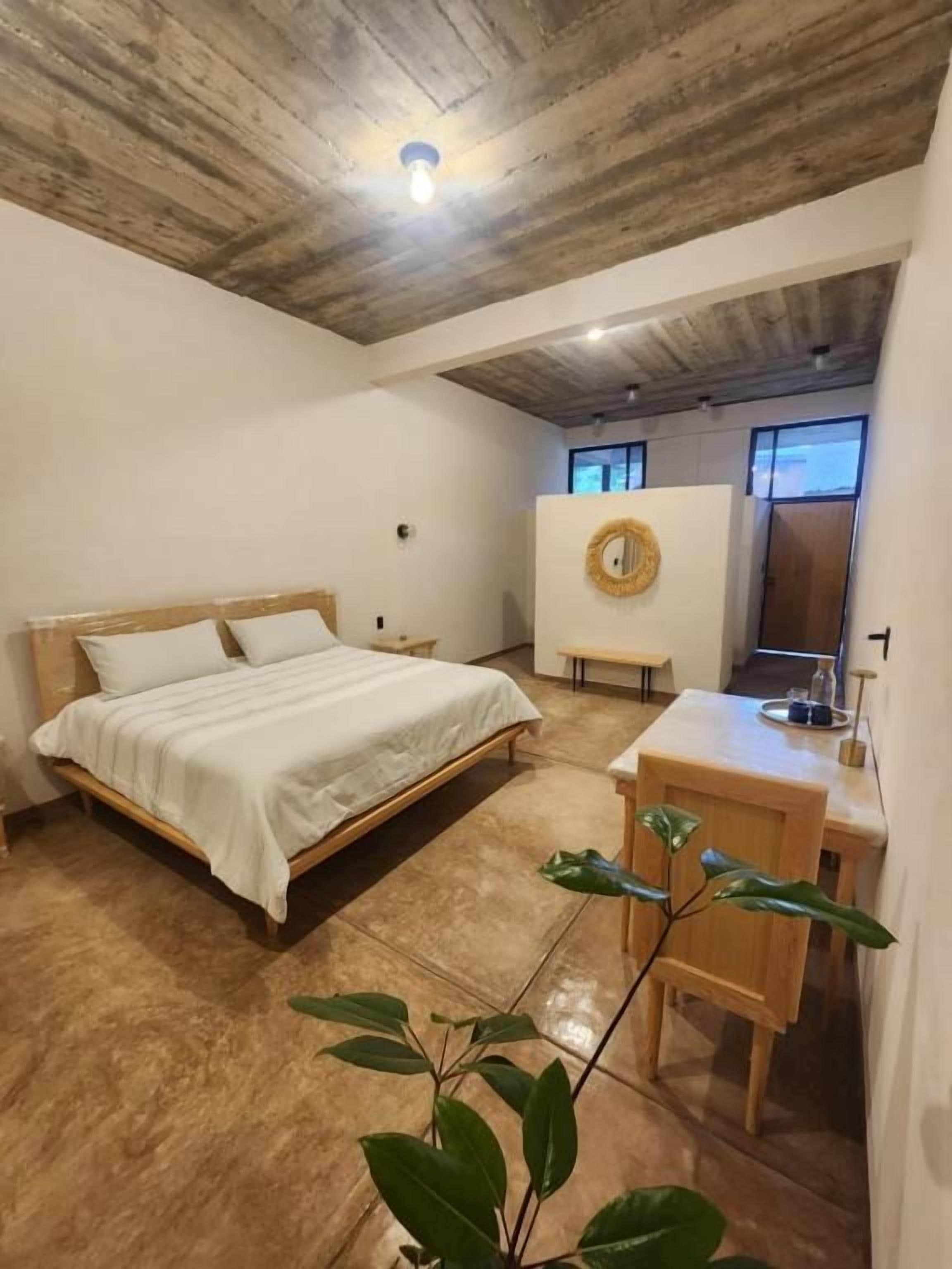 Un dormitorio con techo de madera, una cama, un escritorio y una silla.