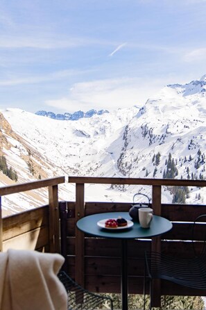 A wooden deck with a table and chairs, overlooking a snow-covered mountain range. - 10m from ski slopes, swimming pool, balcony, ski locker, 30m², Avoriaz (Avoriaz)