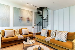 A modern living room with two sofas, a round coffee table, and a spiral staircase. - Daydream in Villa Pozzi by MyHomeInComo (Blevio)