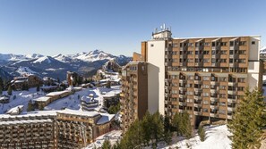 A hotel with multiple floors, a ski resort in the background, and snow-covered mountains. - 10m from ski slopes, view mountain, swimming pool, balcony, ski locker, 30m², Avoriaz (Avoriaz)
