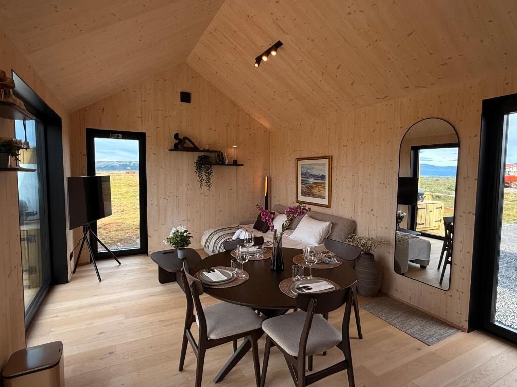 Een houten interieur met een eethoek, een bank en een groot raam met uitzicht.