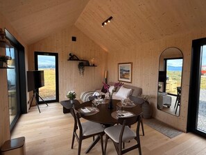 Een houten interieur met een eethoek, een bank en een groot raam met uitzicht.