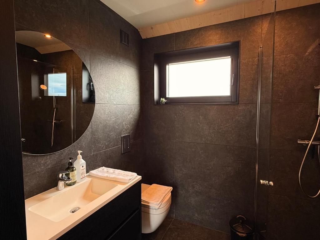Een moderne badkamer met een grote spiegel, een wastafel, toilet en douche.