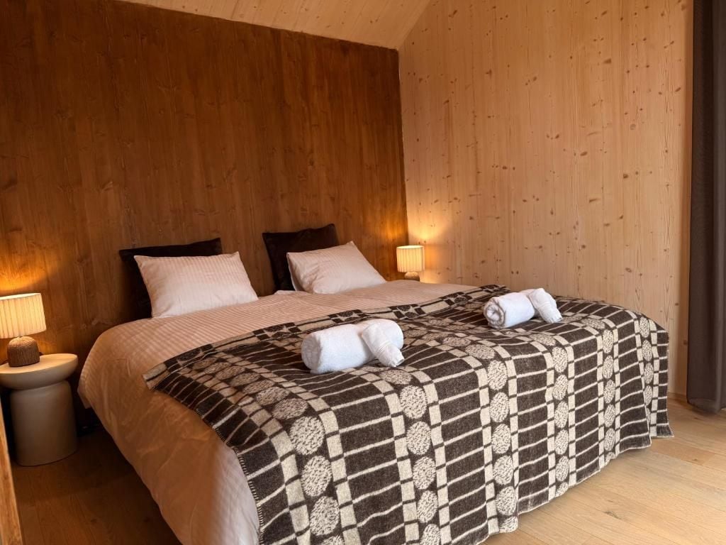 Une chambre à coucher avec un grand lit, deux tables de chevet et une tête de lit en bois.