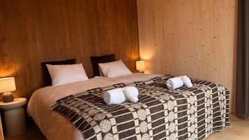 Une chambre à coucher avec un grand lit, deux tables de chevet et une tête de lit en bois.