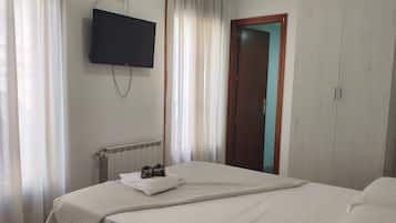 Ett hotellrum med en säng, en tv som är monterad på väggen, en garderob och en dörr.