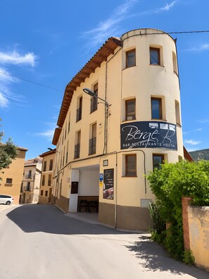 Een gebouw met een bord waarop 'Berge Bar-Bistro Hostal' staat, wat aangeeft dat het een restaurant en hostel is.