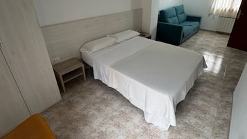 Un dormitorio con cama, mesita de noche, silla, sofá y radiador.