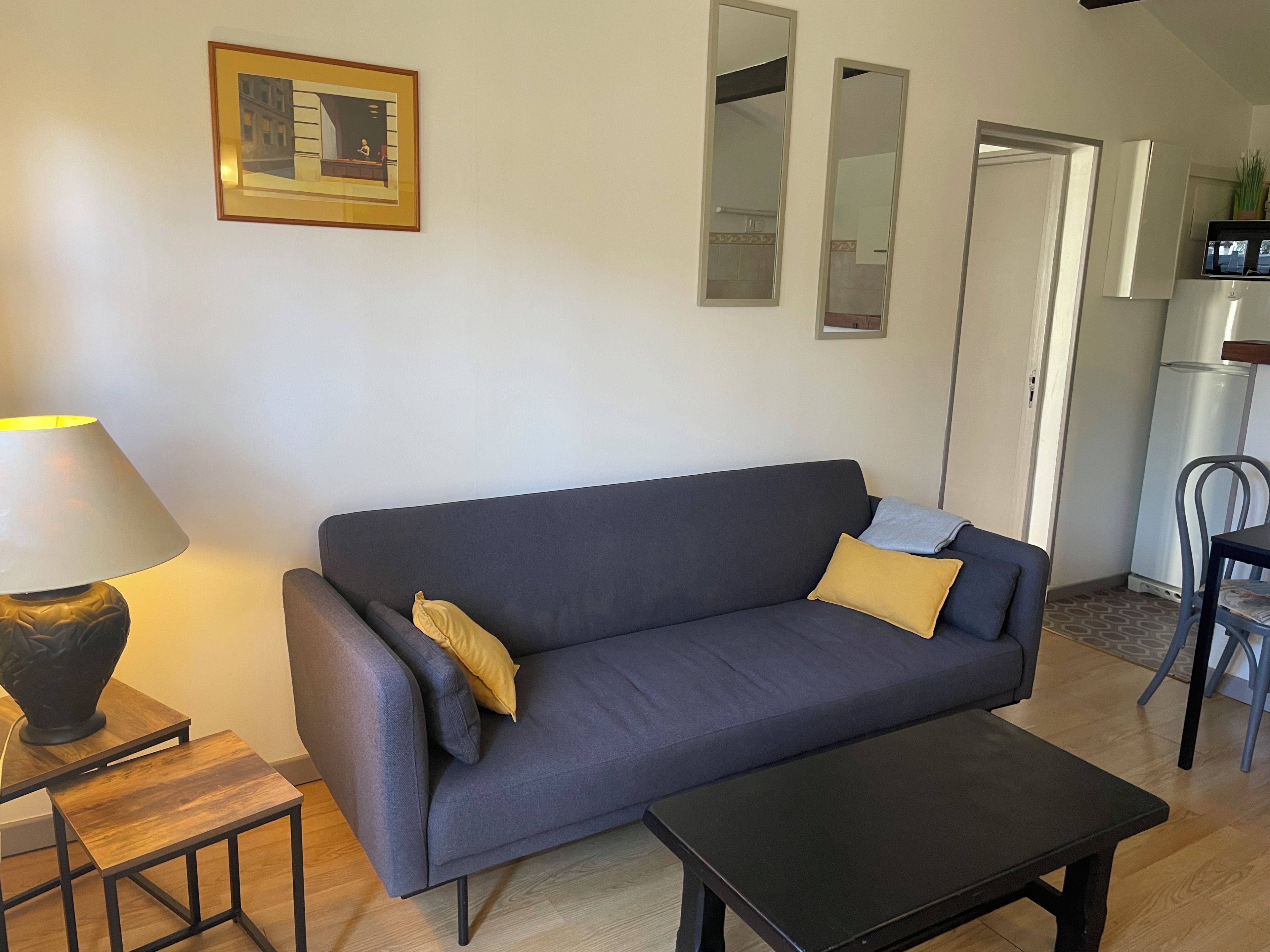 Un salon avec un canapé, une table basse, une lampe et un tableau encadré au mur.