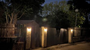 A gated entrance with a metal fence and a wooden fence on one side, a street lamp, and trees in the background. - Charming Little House in Avignon (Montfavet Neighborhood) - Pets Allowed (Avignon)