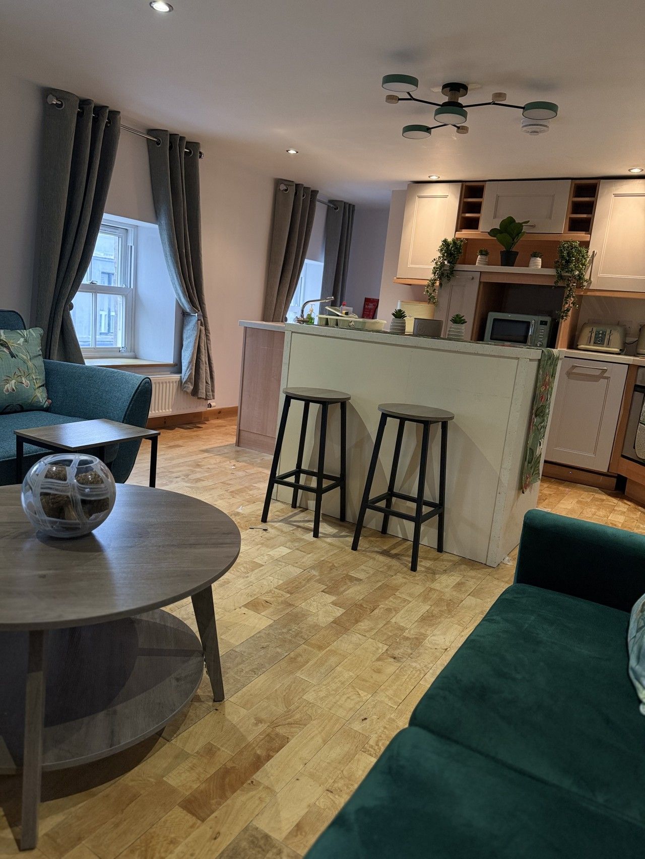 Una sala de estar moderna con un sofá, una mesa redonda y una cocina con un taburete de bar.