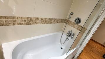 Un bagno moderno con una vasca freestanding, uno spazio doccia in vetro e un pavimento piastrellato.