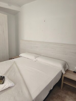 Una camera da letto con un letto, un comodino e una presa elettrica.