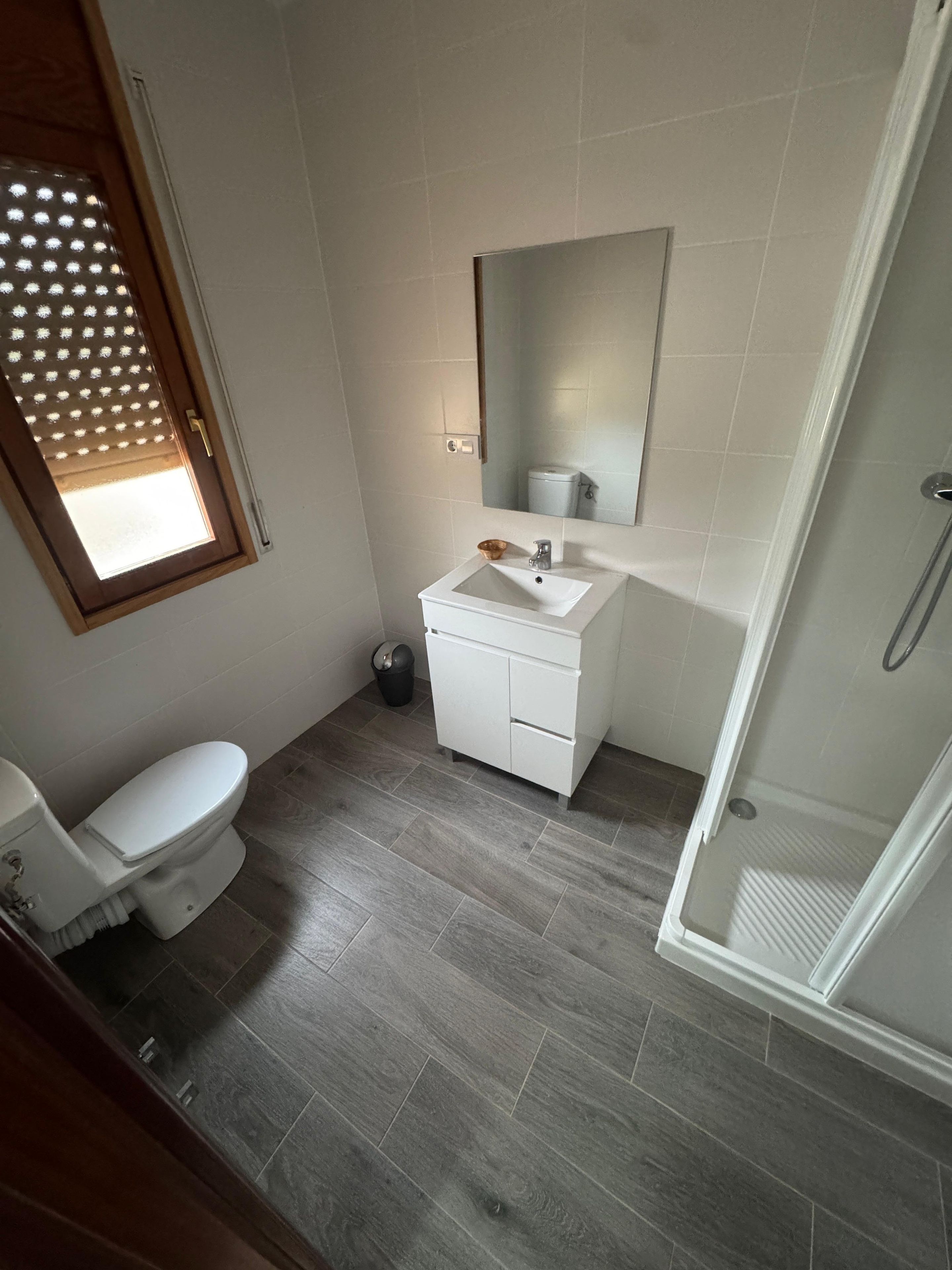 Un baño con inodoro, lavamanos, espejo y ducha.