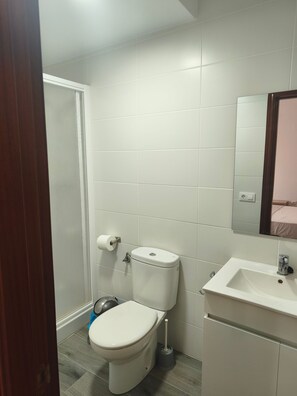 Un bagno con il water, lavandino e specchio.