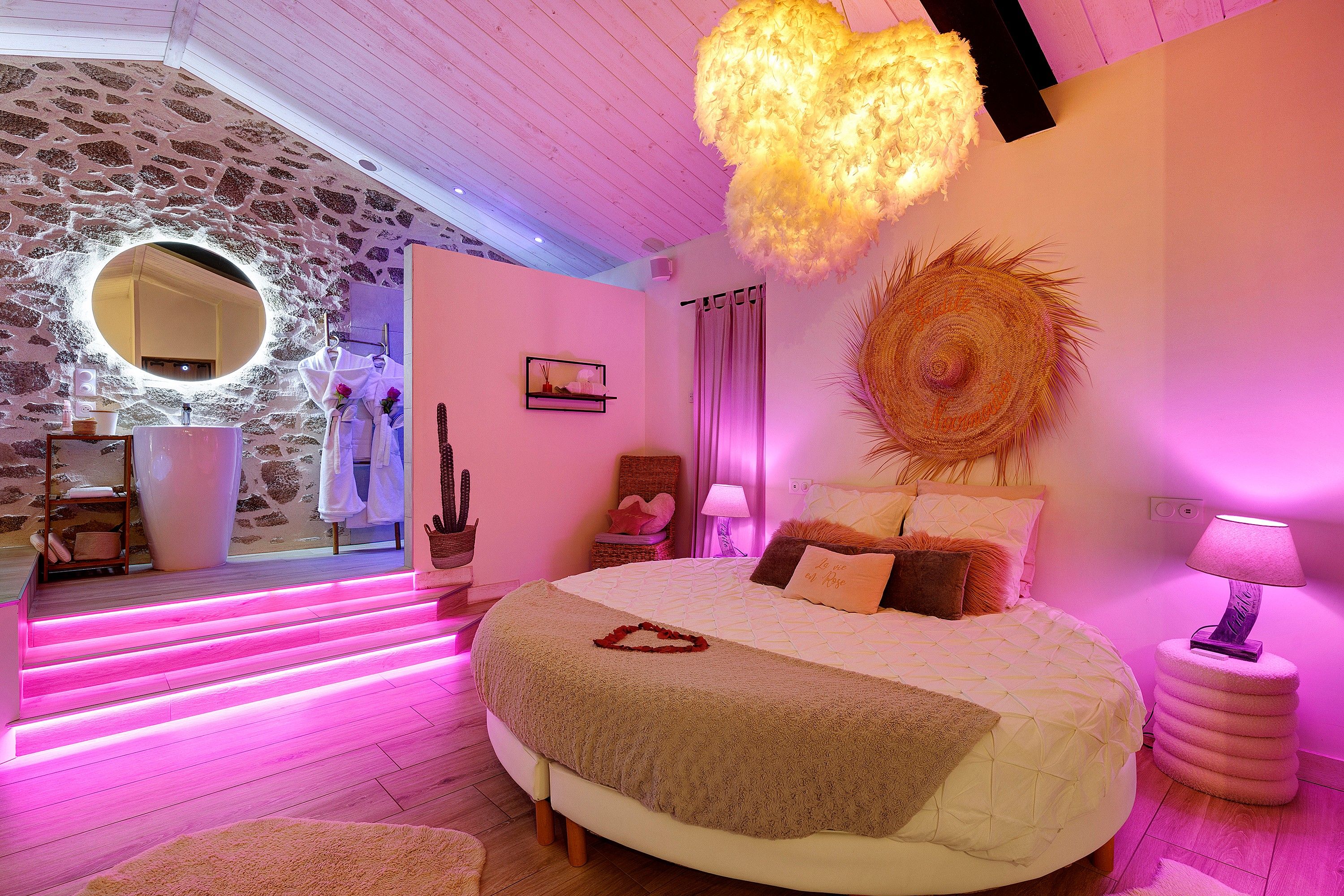 Een slaapkamer met een groot bed, een ronde spiegel en een wandlamp.