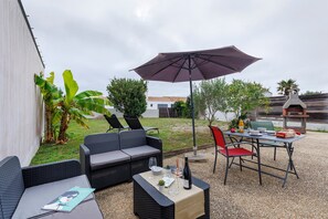 An outdoor patio with wicker furniture, a table set for dining, and a grill.