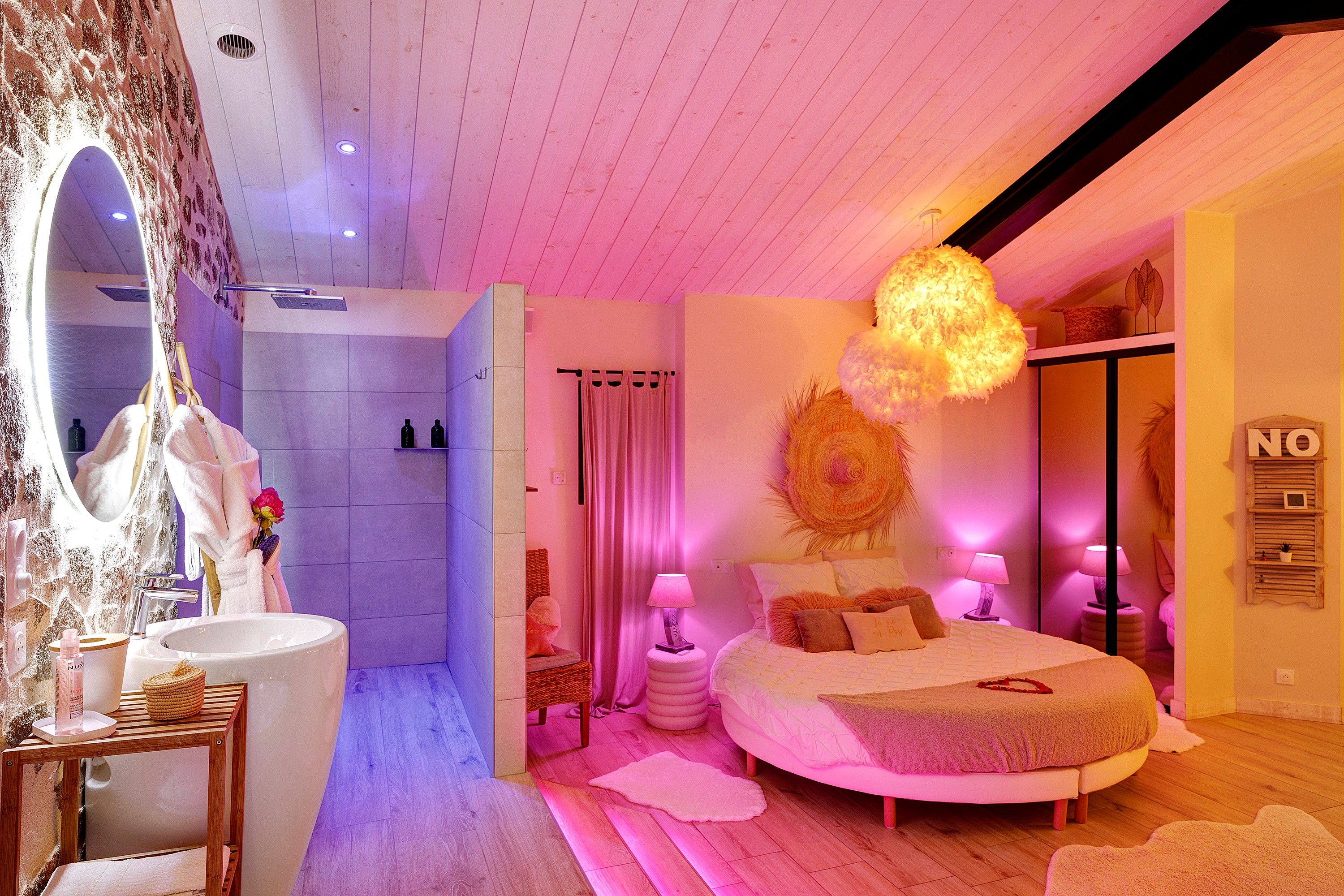 Een slaapkamer met een groot bed, een kaptafel met spiegel en een douchegedeelte.