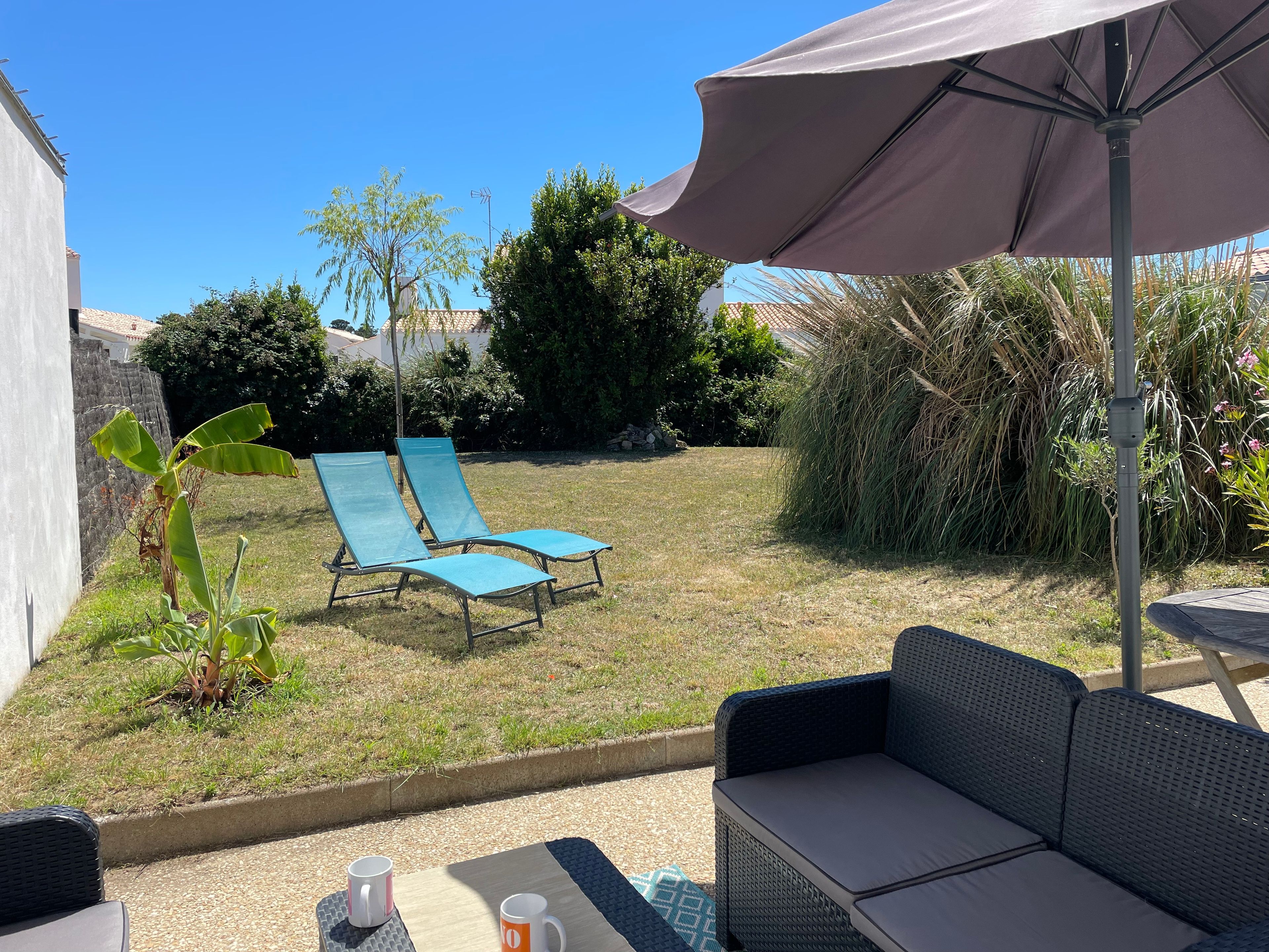 Een terras met een tafel, twee lounge stoelen en een grote parasol.
