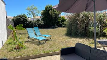 Een terras met een tafel, twee lounge stoelen en een grote parasol.