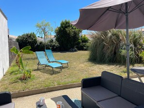 A patio area with a table, two lounge chairs, and a large umbrella.