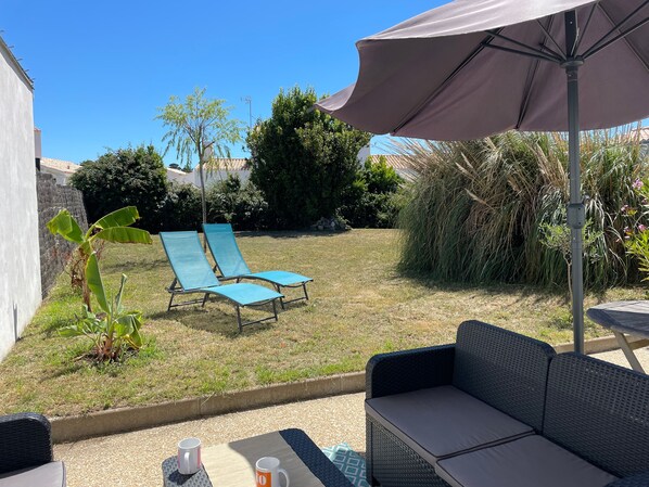 A patio area with a table, two lounge chairs, and a large umbrella.