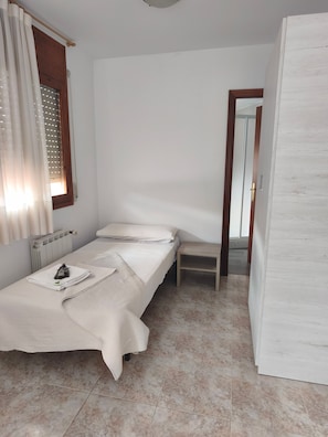 Een compacte, verzorgde slaapkamer met een enkel bed, een nachtkastje en een radiator.