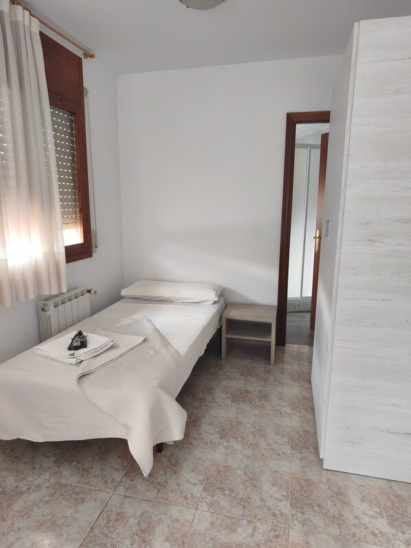 Una camera da letto piccola e curata, con un letto singolo, un comodino e un termosifone.