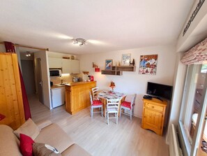 Un espace de vie compact comprenant une kitchenette, un coin repas et un téléviseur.