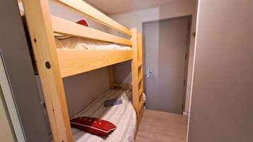 A bunk bed with a wooden frame, a door, and a small storage space.