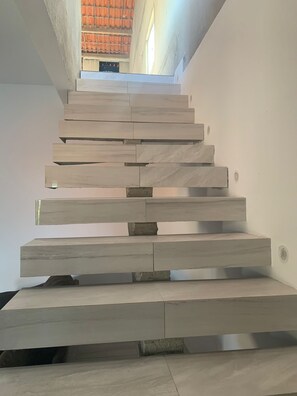A modern staircase with a minimalist design, made of light-colored stone or concrete, leading to an upper floor. - Cozy house in Ceará (Caponga)