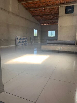 A spacious room with a tiled floor, a mattress, a chair, and a window. - Cozy house in Ceará (Caponga)