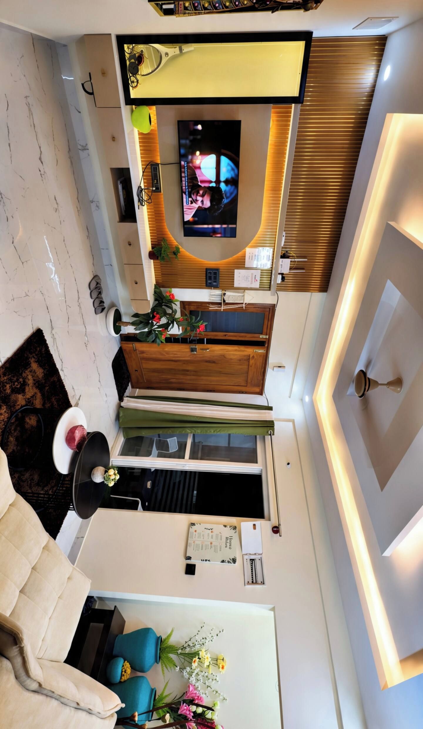 A modern living room with a flat-screen TV mounted on the wall, a wooden cabinet, and a sofa.