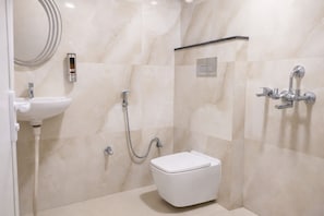 A bathroom with a toilet, a sink, and a shower unit. - Shri Hari Guesthouse (Varanasi)