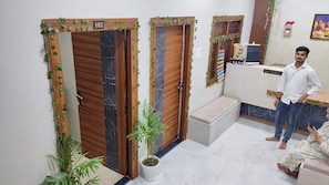 A reception area with wooden doors numbered 102 and 103, a reception desk, and a bench. - Shri Hari Guesthouse (Varanasi)
