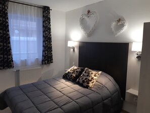 Een slaapkamer met een bed, twee decoraties in de vorm van harten en bedlampen.