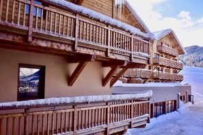 A wooden chalet with balconies, a window, and snow-covered surroundings. - T2 au Pied des Pistes | Espace bien-être (Combloux)