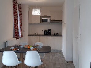 A compact kitchen with a microwave, coffee maker, and a dining table with chairs. - Directement sur les pistes | Piscine | Balcon (Combloux)