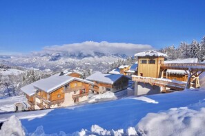 A snow-covered mountain resort with wooden chalets and a wooden tower, surrounded by snow-covered trees and mountains. - Directement sur les pistes | Piscine | Balcon (Combloux)