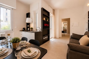 A modern living space with a dining area, kitchenette, and a cozy seating area. - Newly Designed Apartment with Balcony, 10-Minute Walk to Bocconi, Sleeps 4 (Milan)