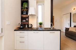 A modern kitchen with a built-in island, white cabinetry, and a black countertop. - Newly renovated apartment with a balcony, a 10-minute walk to Bocconi, sleeps 4 (Milan)