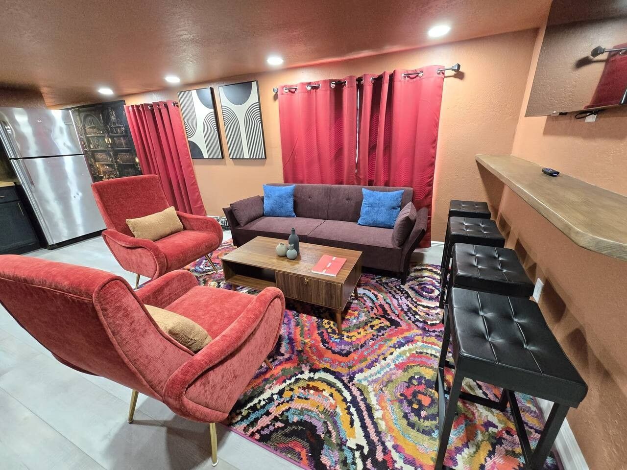 Un espace de vie compact comprenant un canapé, deux fauteuils, une table basse et un petit coin bar.