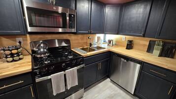 Une cuisine moderne avec des meubles de couleur sombre, des appareils en acier inoxydable et un plan de travail en bois.