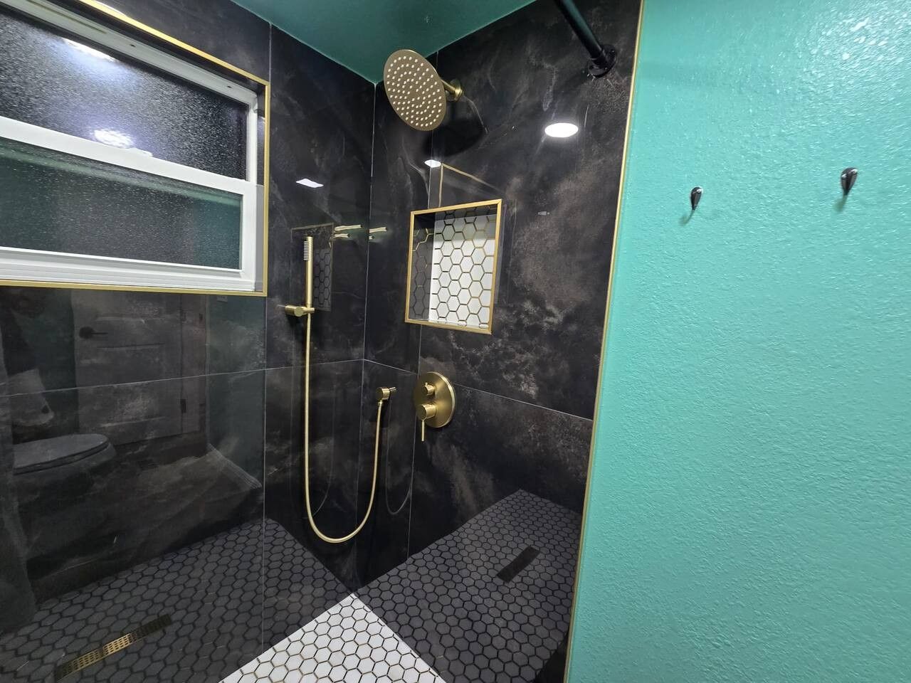Une salle de bain avec une douche, des toilettes et une fenêtre.