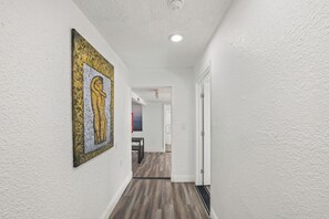 A hallway with white walls, a wooden floor, and a painting on the left. - 3-bedroom apartment with AC near Brickell/Downtown (Miami)