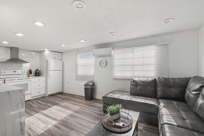 A modern kitchen with white appliances, a dining area with a leather sofa, and a window with blinds. - 3-bedroom apartment with AC near Brickell/Downtown (Miami)