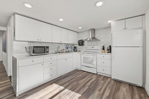 A modern kitchen with white cabinets, a built-in microwave, a stove, and a refrigerator. - 3-bedroom apartment with AC near Brickell/Downtown (Miami)