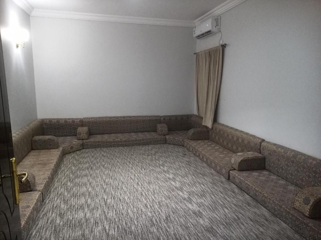 Una habitación con un amplio suelo alfombrado y un sofá modular empotrado.