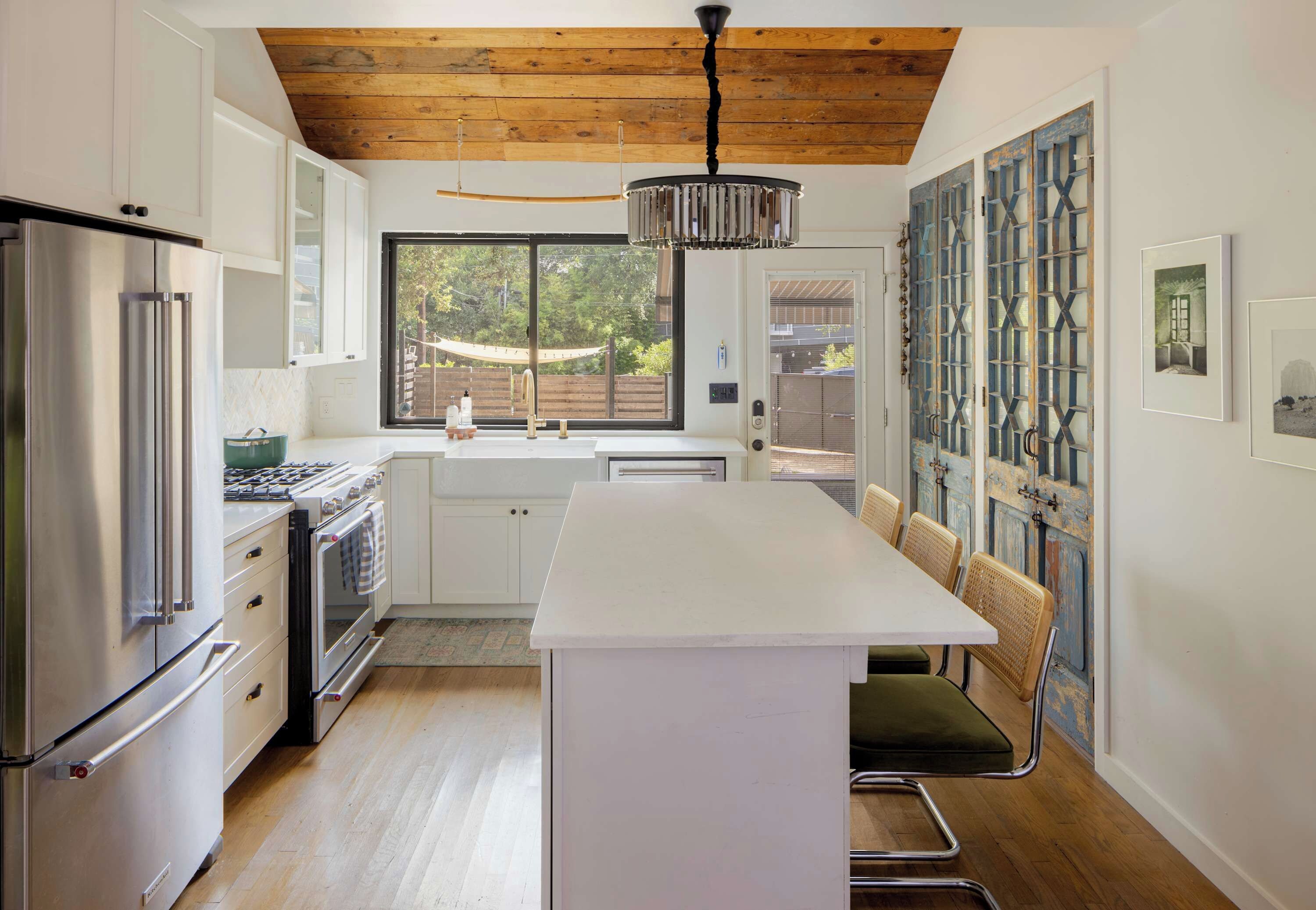A modern kitchen with a central island, stainless steel appliances, and a large window.